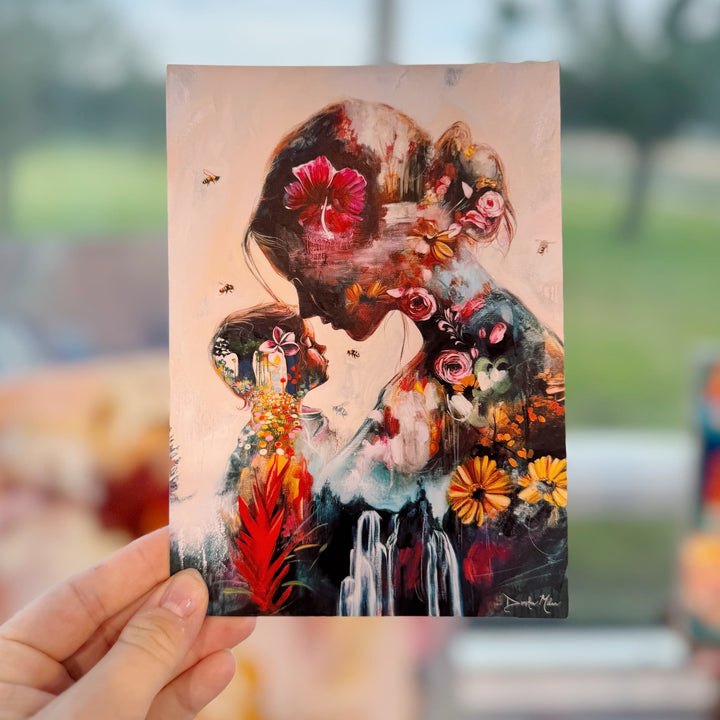 Artistic depiction of a person with floral and abstract elements held by a hand against a blurred outdoor background.